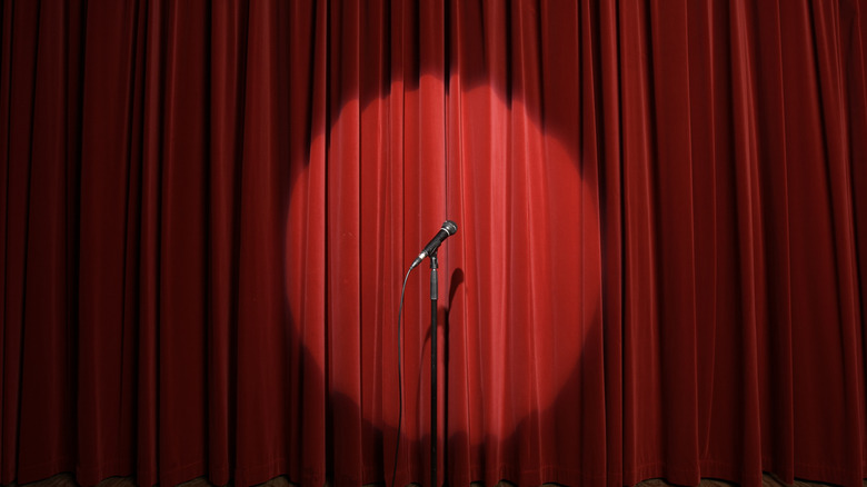 Microphone in front of a red curtain with a spotlight on it.