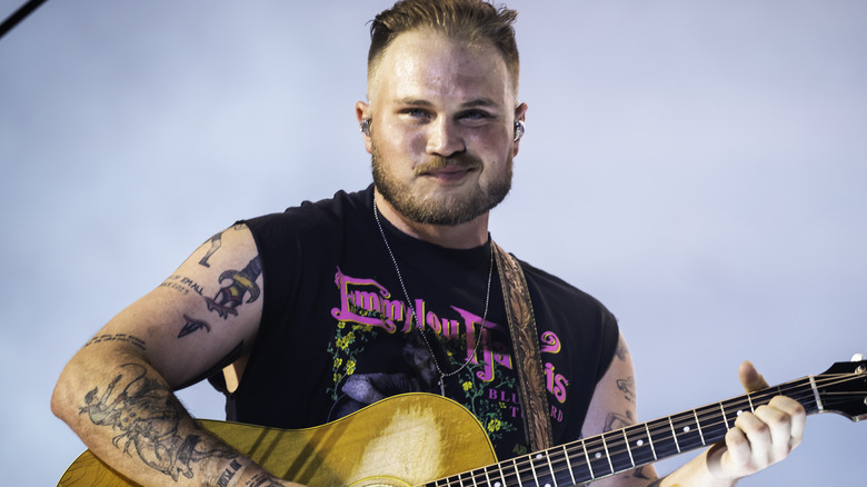 Zach Bryan on stage with a grey background
