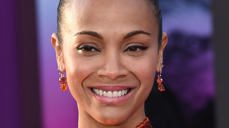 Zoe Saldana wears orange drop earrings and smiles