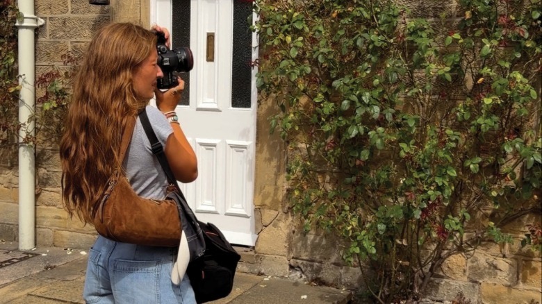 Ella Gaines stands holding a camera to her face