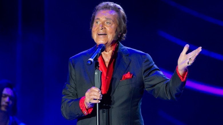 Engelbert Humperdinck speaking into a microphone while gesturing