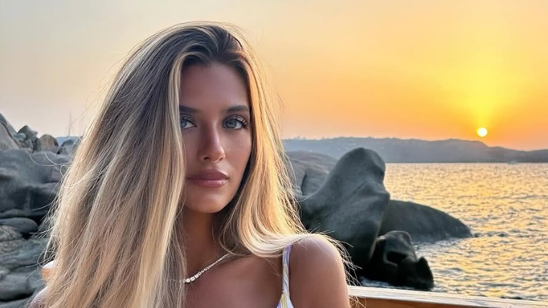 Isabella Lamas poses by the ocean with a setting sun.