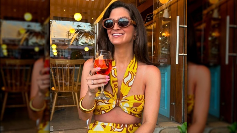 Kaitlan Collins posing with a drink in hand.