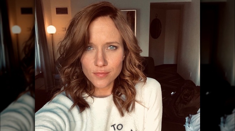 Jessy Scram takes a selfie with brown curled hair.