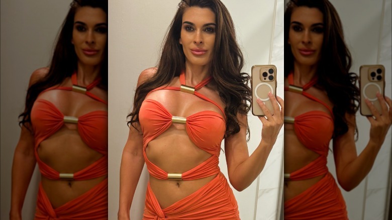 Shawna Craig takes a mirror selfie in a coral-colored dress with cutouts.