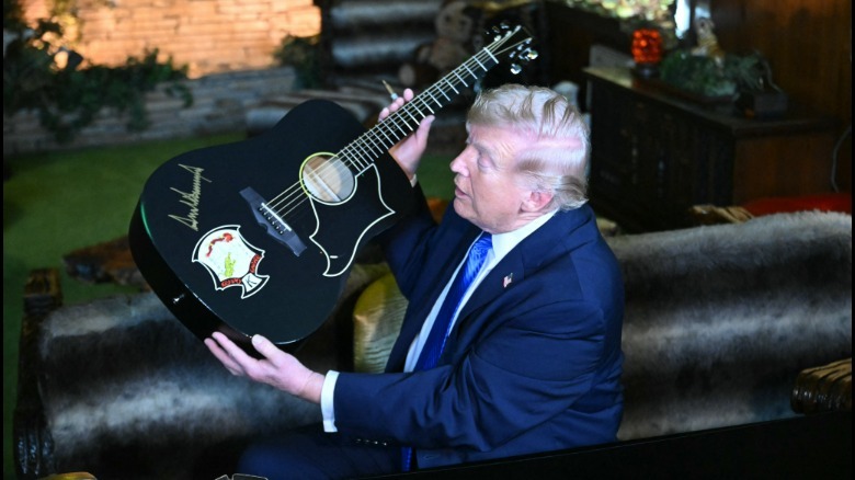 US President Donald Trump shows a replica of one of Elvis Presley guitars after he signed it
