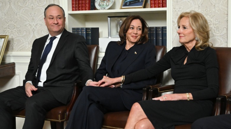 Jill Biden holdings hands with Kamala Harris and Doug Emhoff