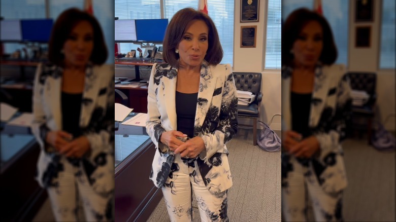 Jeanine Pirro speaking to her followers wearing a black and white floral suit