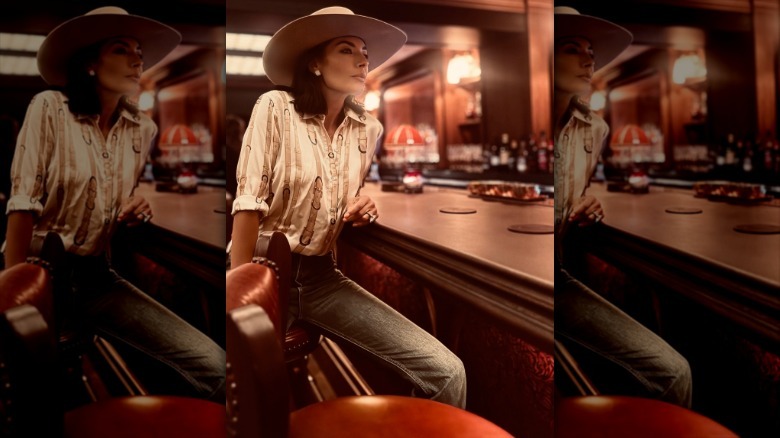 Nicole Muirbrook wearing a cowboy hat and jeans at a bar